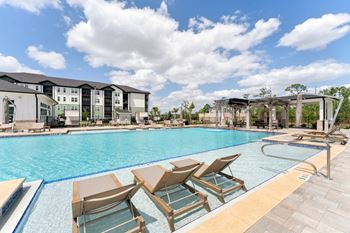 A pool with chairs and a building in the background.